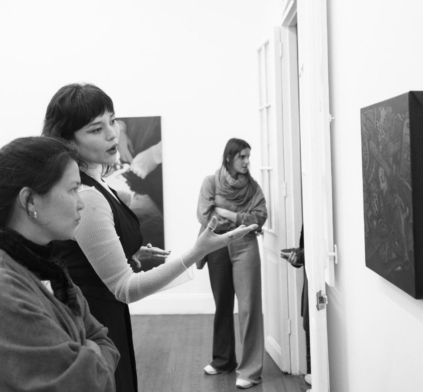 Visitantes conversan frente a obras en una sala de exposición